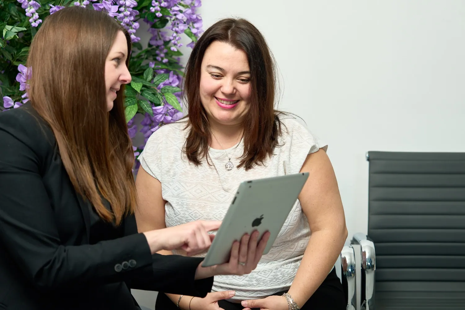 A patient coordinator going through information on a tablet with a smiling patient